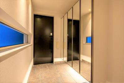 玄関：玄関の床材は300×600サイズの高級感溢れる仕様。シューズボックスの鏡で広がりも感じる